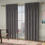 A pair of charcoal gray pinch-pleat curtains framing a large window in a modern living room.
