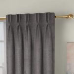 Close-up of charcoal gray pinch-pleated curtains hanging from a decorative gold rod.
