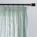 Detail shot of the pleated header and black curtain rings on a metal rod.