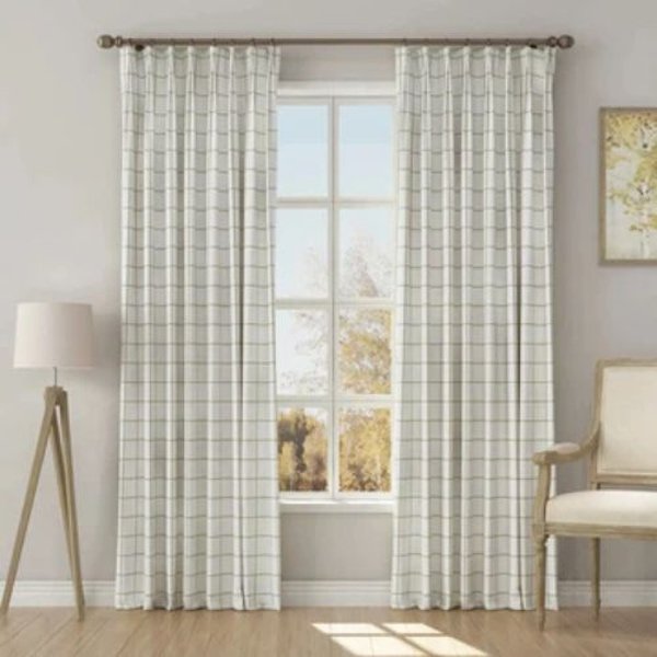 Full-length view of white grid curtains framing a large window in a bright, neutral-toned living room.