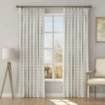 Full-length view of white grid curtains framing a large window in a bright, neutral-toned living room.