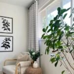 White grid curtains hung floor-to-ceiling in a cozy corner next to a large indoor plant and framed wall art.