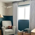 White grid curtains in a nursery featuring dark teal wainscoting and star-patterned wallpaper.